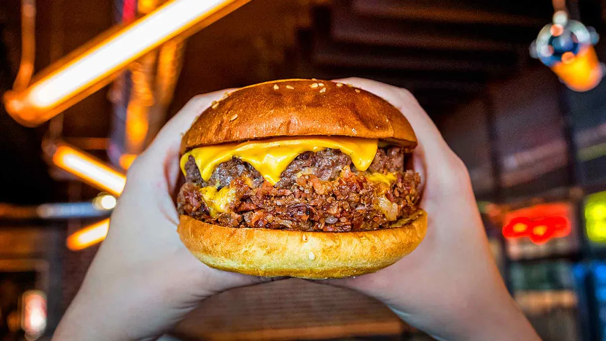 Hamburguesa con queso sujeta con las manos en Goiko, hamburguesería de Salamanca